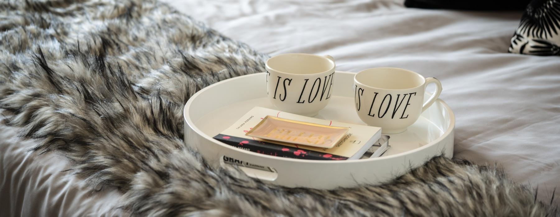 coffee mugs on a tray resting on bed